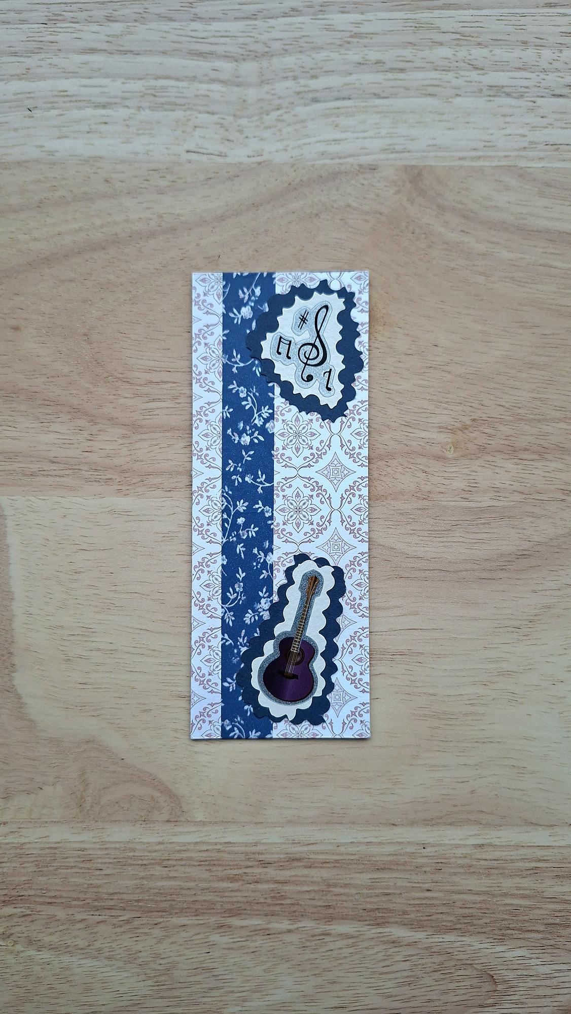 Front of vintage-style music bookmark with blue floral stripe, musical notes and guitar.