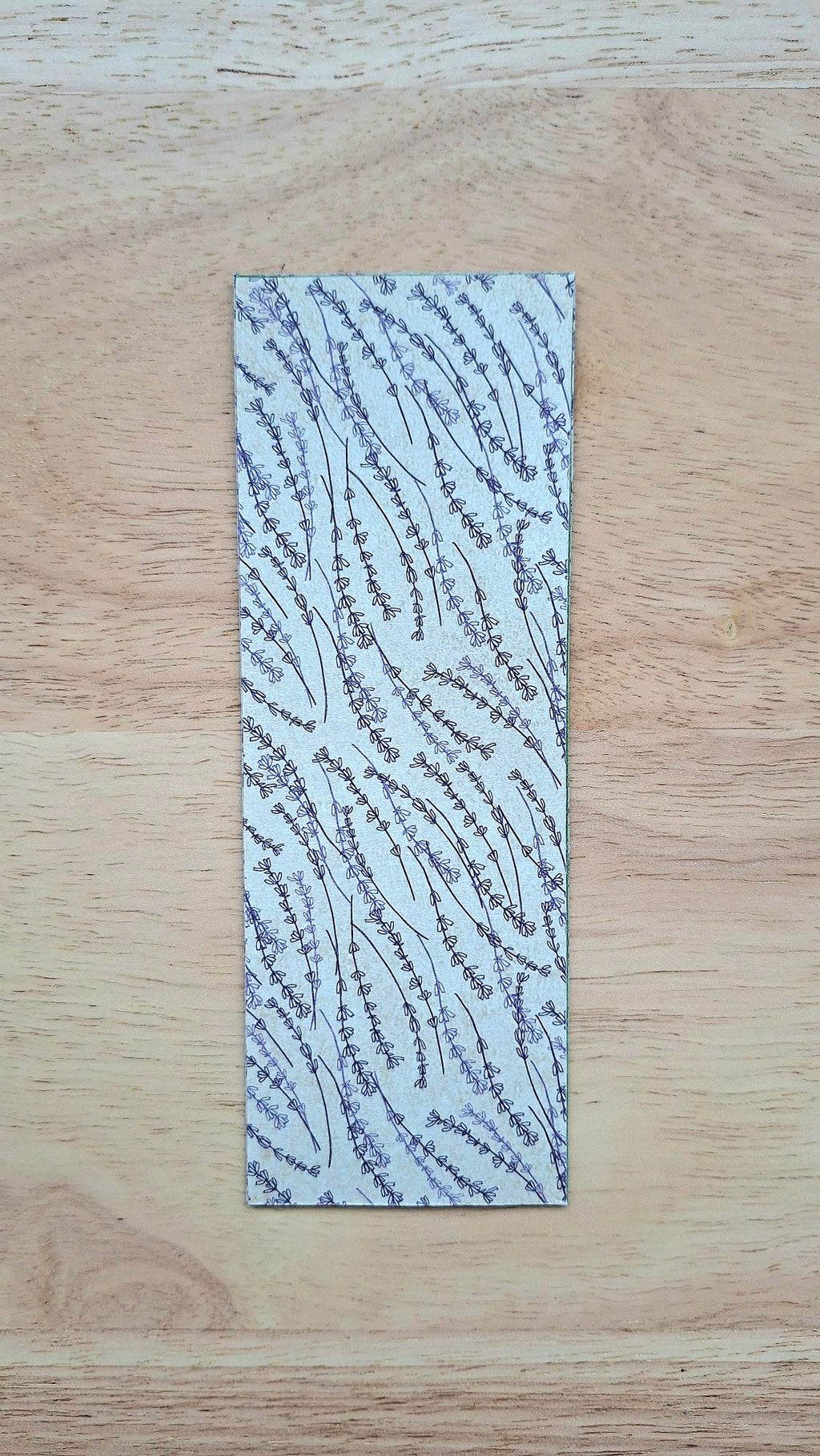 Bookmark reverse with delicate purplish floral stems on a beige background.