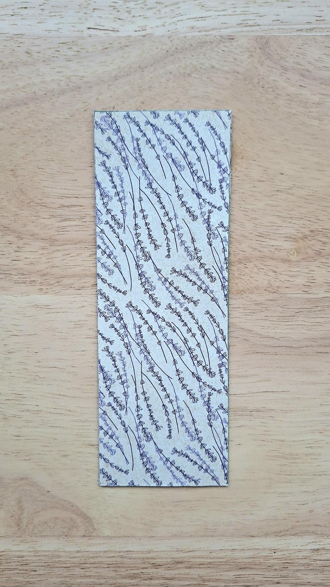 Bookmark reverse with delicate purplish floral stems on a beige background.