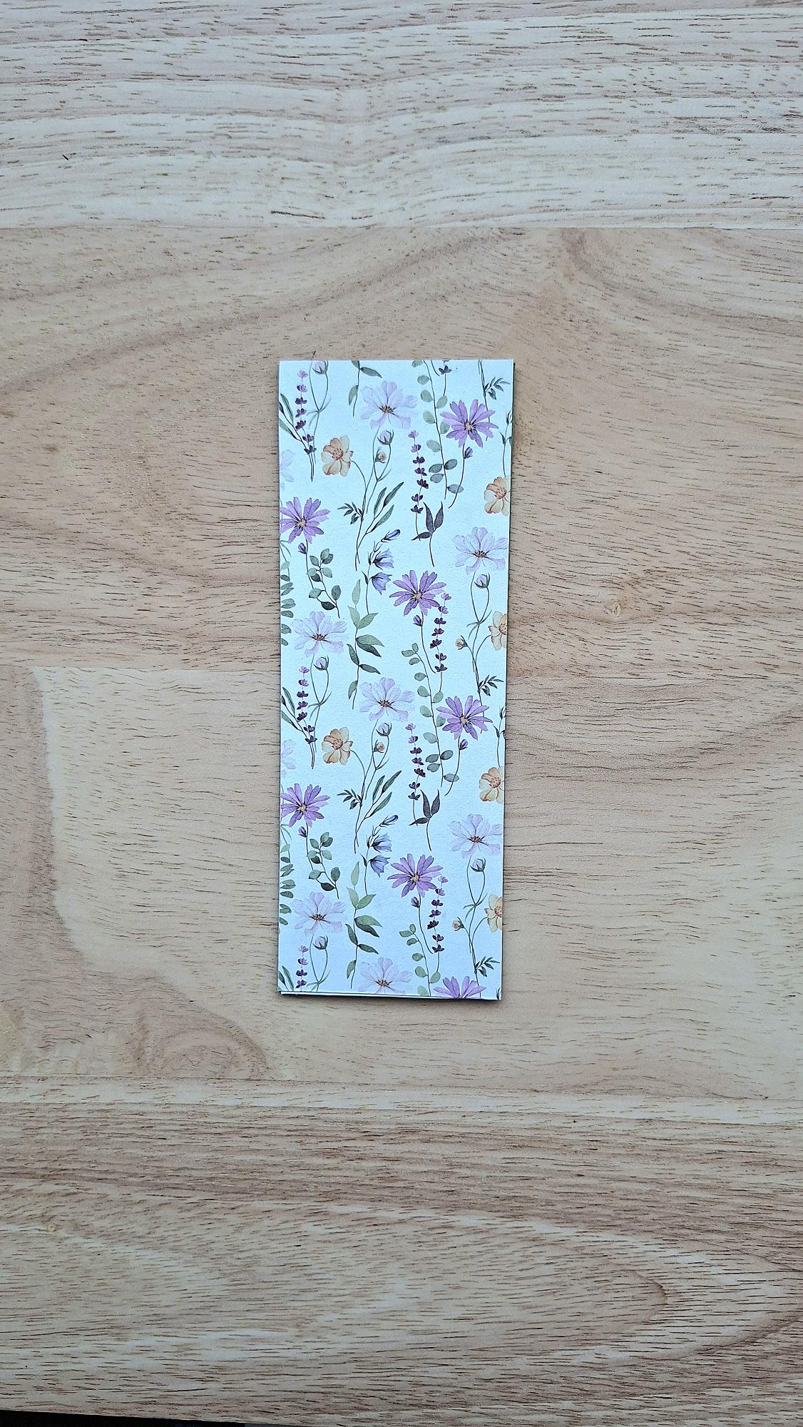 Bookmark reverse with delicate purple flowers and green foliage on a pale background.
