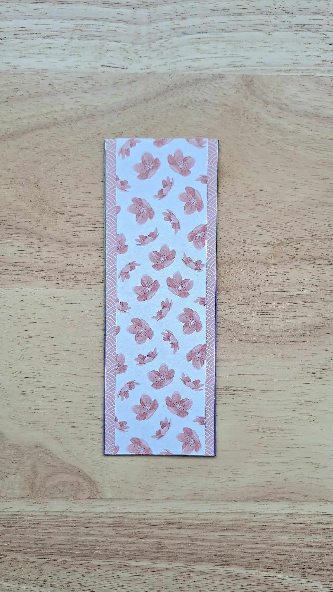 Bookmark reverse with dusty-pink flowers on a pale background and patterned borders.